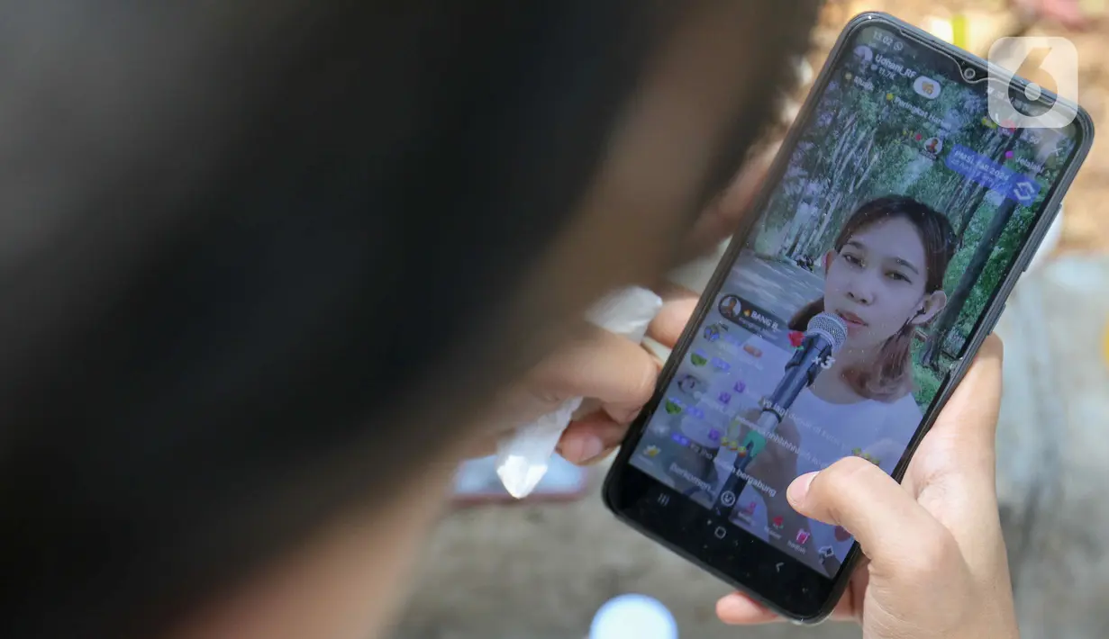 Layar ponsel menampilkan live streaming" TikTok seorang konten kreator TikTok yang bernyanyi di kawasan Kanal Banjir Timur (KBT), Duren Sawit, Jakarta Timur, Sabtu (7/9/2024). (Liputan6.com/Herman Zakharia)