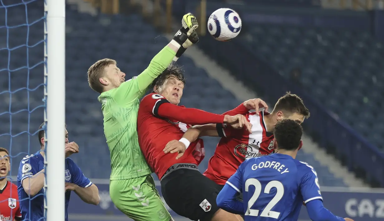 Kiper Everton, Jordan Pickford (kiri) meninju bola dari ancaman pemain Southampton dalam laga lanjutan Liga Inggris 2020/21 pekan ke-26 di Goodison Park, Liverpool, Senin (1/3/2021). Everton menang 1-0 atas Southampton. (AP/Clive Brunskill/Pool)
