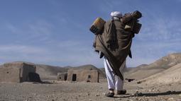 Hajji Wali Jan (66) membawa wadah plastik untuk air dalam perjalanan ke rumahnya di desa Kamar Kalagh di luar Herat, pada 26 November 2021. Kekeringan Afghanistan, yang terburuk dalam beberapa dekade, kini memasuki tahun kedua, diperburuk oleh perubahan iklim. (AP Photo/Petros Giannakouris)