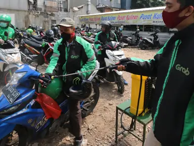 Pengemudi ojek online melakukan penyemprotan disinfektan sebelum mengangkut penumpang di Shelter Sudirman, Jakarta, Senin (8/6/2020). Pemprov DKI mulai mengizinkan ojek daring maupun konvensional mengangkut penumpang di PSBB transisi dengan menerapkan protokol kesehatan. (Liputan6.com/Angga Yuniar)