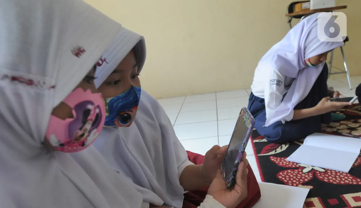Murid-murid SD dan SMP belajar dengan memanfaatkan wifi gratis di Balai RW kawasan Tegal Gundil, Bogor, Jawa Barat, Senin (21/9/2020). Pemkot Bogor menyebar lebih dari 50 titik wifi publik gratis untuk menunjang Pembelajaran Jarak Jauh (PJJ) siswa di Kota Bogor. (merdeka.com/Arie Basuki)