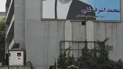Pejuang Taliban berpatroli melewati poster Presiden Afghanistan Ashraf Ghani yang digulingkan di Kabul (17/8/2021). Taliban bergerak untuk segera memulai kembali ibu kota Afghanistan setelah pengambilalihan Kabul n dan menyuruh staf pemerintah untuk kembali bekerja. (AFP/Wakil Kohsar)