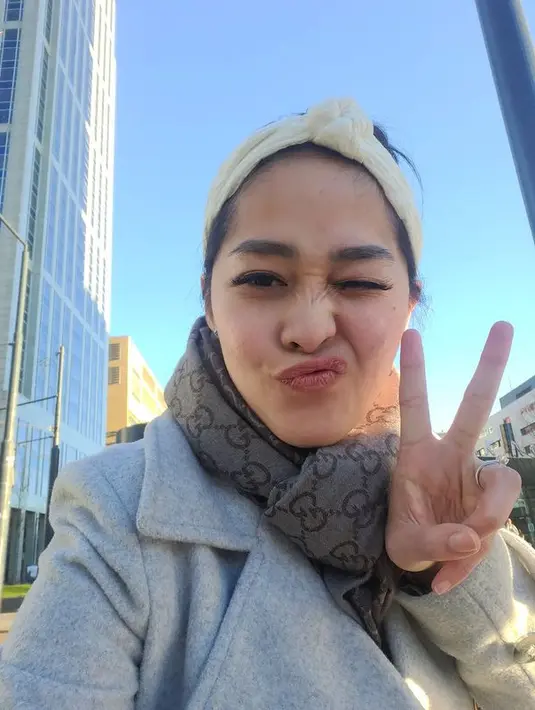 Berlatar langit biru, Gracia Indri selfie mengenakan wool coat berwarna abu-abu yang dipadukan dengan syal dari Gucci. Ia juga mengenakan aksesori puffy bandana berwarna putih (instagram/graciaz14)