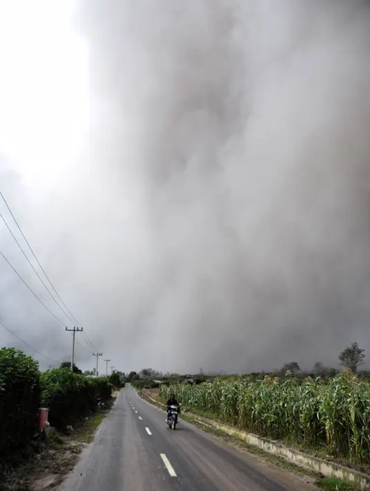 Seorang pengendara motor melintas di dekat kawasan Gunung Sinabung yang kembali mengalami erupsi, Karo, Sumatera Utara (31/10). Masyarakat di dekat gunung tertinggi di Sumut diimbau untuk menjauhi zona merah. (AFP Photo/Satar Ginting)