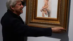 Seorang kurator galeri memasang lukisan kandidat Presiden AS dari Partai Republik, Donald Trump dalam keadaan telanjang, di Galeri Maddox, London, Sabtu (9/4). Lukisan karya Illma Gore itu diberi judul “Make America Great Again” (Niklas HALLE'N/AFP)