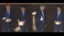 Dalam gambar kombinasi yang dibuat dari video, Presiden AS Donald Trump, bersama PM Jepang Shinzo Abe mmeberi makan ikan koi di kolam Istana Akasaka, Tokyo, Senin (6/11). PM Abe dan juga Trump menuangkan seluruh sisa makanan ikan di kotak . (AP Photo)