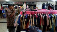 Pengunjung mencoba pakaian bekas impor yang dijajakan pedagang di Pasar Baru Metro Atom, Jakarta, Jumat (6/12/2019). Pakaian bekas impor yang dijual di kios-kios pasar masih banyak diminati lantaran harga yang ditawarkan sangat terjangkau. (merdeka.com/Imam Buhori)