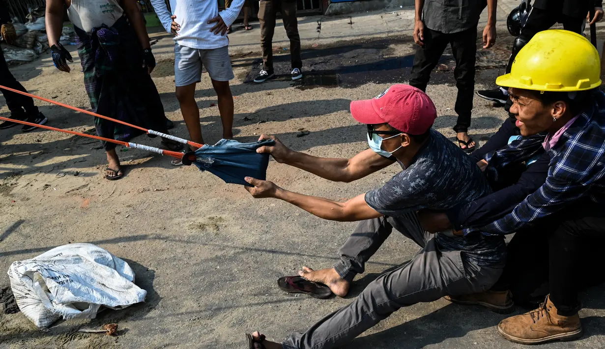 Para pengunjuk rasa menguji senjata ketapel besar ketika pasukan keamanan melanjutkan tindakan keras terhadap demonstrasi menentang kudeta militer di Yangon, Rabu (17/3/2021). (AFP/STR)