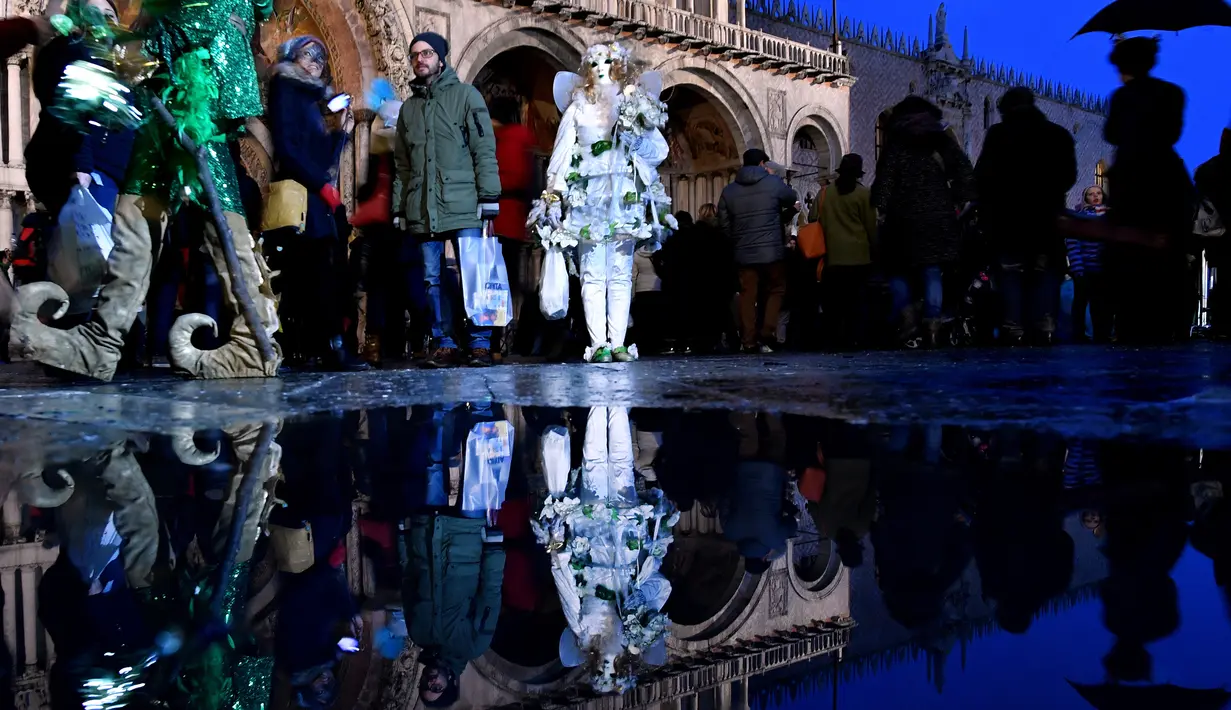 Peserta mengenakan kostum dan topeng saat mengikuti karnaval tradisional Venesia di Italia (27/1). Karnaval Venesia adalah festival yang rutin diadakan setiap tahunnya di kota Venesia, Italia. (AFP Photo/Filippo Monteforte)