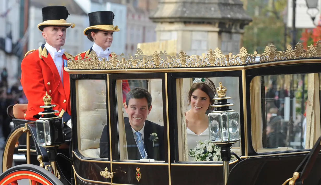 Putri Eugenie dan Jack Brooksbank menaiki kereta kencana usai melangsungkan pernikahan di Kapel St. George, Windsor Castle, London, Inggris,  Jumat (12/10). Putri Eugenie merupakan anak bungsu Pangeran Andrew dan Sarah Ferguson. (AP Photo/Rui Vieira)