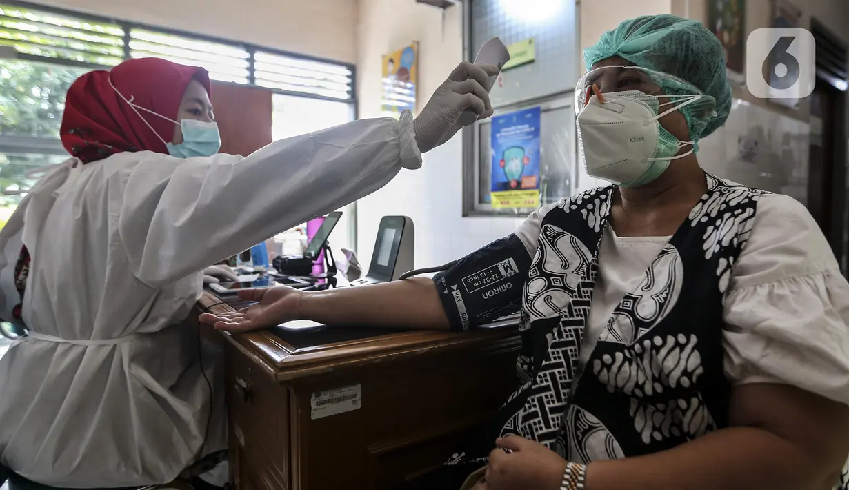 Petugas medis memeriksa suhu tubuh tenaga kesehatan sebelum disuntik vaksin COVID-19 Sinovac di Puskesmas Palmerah, Jakarta, Kamis (28/1/2021). Pemberian vaksin COVID-19 tahap kedua dilaksanakan terhadap tenaga kesehatan mulai hari ini. (Liputan6.com/Johan Tallo)