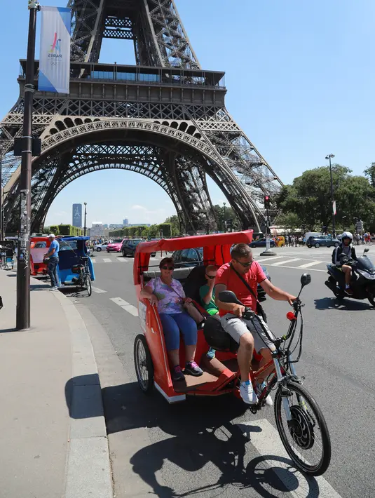 Wisatawan berkeliling kota Paris menggunakan transportasi becak, Prancis, (7/7). Menurut media setempat, kemunculan becak ini membuat para sopir taksi memiliki saingan. (AFP Photo/Jacques Demarthon)