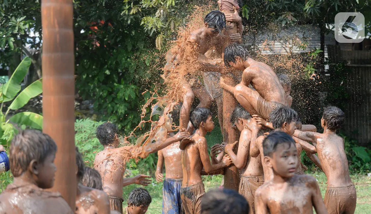 Sejumlah peserta bahu-membahu dalam perlombaan panjat pinang di Kampung Bulak, Kelurahan Benda Baru, Pamulang, Tangerang Selatan, Senin (17/8/2020). Lomba di tengah masa pandemi itu guna memeriahkan HUT ke-75 Kemerdekaan RI. (merdeka.com/Dwi Narwoko)