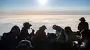 Orang-orang sarapan setelah menyaksikan matahari terbit dari puncak Gunung Fuji, barat Tokyo pada 19 Juli 2021. Mendaki Gunung Fuji bukan hal yang mudah, tetapi pemandangan matahari terbit di atas lautan awan adalah hadiah indah bagi yang mencapai puncak tertinggi di Jepang. (Charly TRIBALLEAU/AFP)