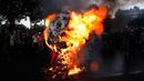 Sebuah topeng raksasa yang menggambarkan Presiden Prancis Emmanuel Macron dibakar selama terjadi demonstrasi di Paris, Prancis (23/5). (AP/Christophe Ena)