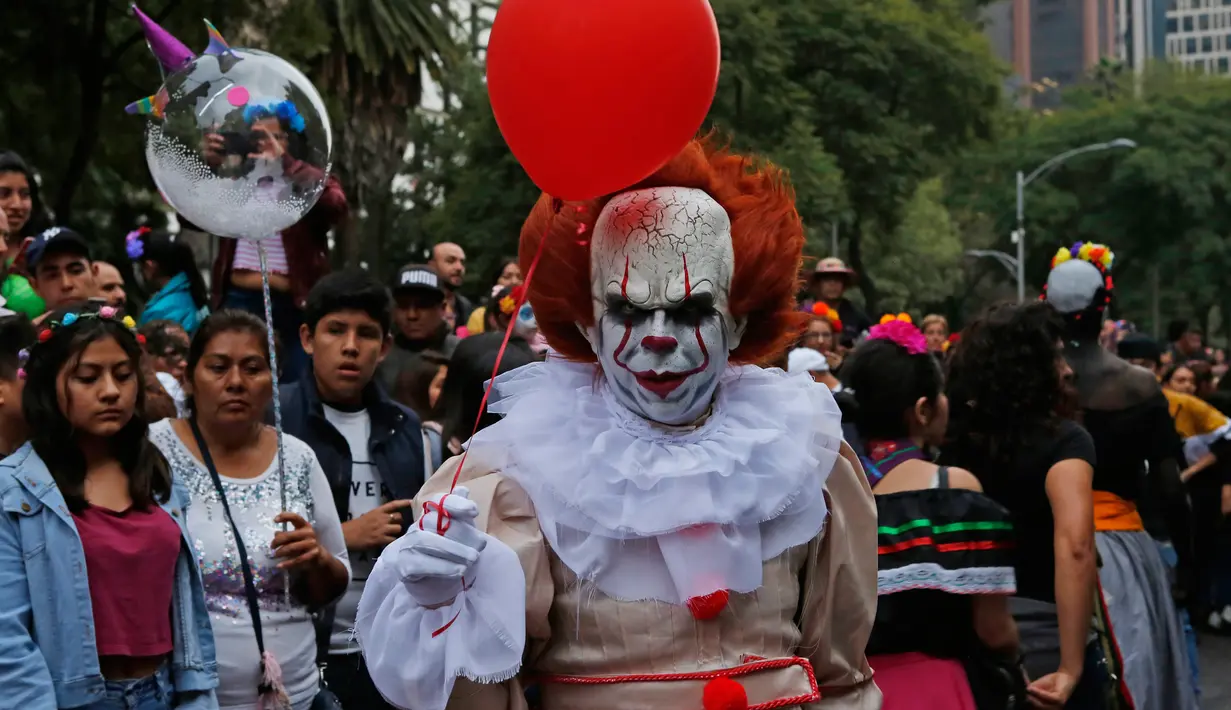 Seorang pria mengenakan kostum tokoh film 'It' saat mengikuti parade Hari Orang Mati di Mexico City, Meksiko, Sabtu (26/10/2019. Para peserta dalam parade ini mengenakan kostum dan melukis wajah mirip dengan tokoh tengkorak Meksiko yang ikonik, Catrina. (AP Photo/Ginnette Riquelme)