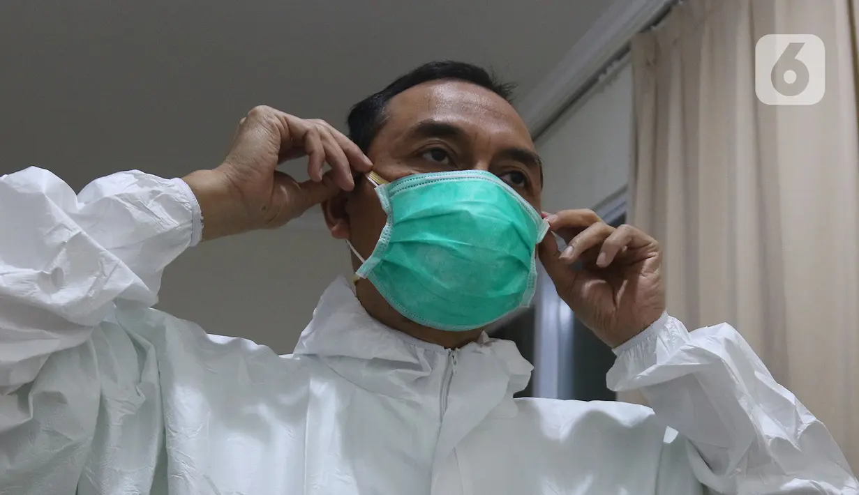dr Rahmadi Iwan Guntoro, Sp.P melapisi masker N95 dengan masker bedah di Rumah Sakit Haji, Jakarta, Kamis (9/4/2020). Gugus Tugas Percepatan Penanganan COVID-19 telah mengeluarkan rekomendasi standar APD berdasarkan tiga tingkatan perlindungan. (Liputan6.com/Herman Zakharia)