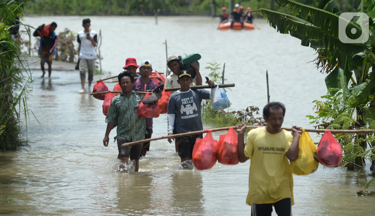 Warga berjalan melintasi banjir di Desa Sindangsari, Kabupaten Bekasi, Jawa Barat, Rabu (24/2/2021). Tim Tanggap Bencana Land Rover Club Indonesia (LRCI) melakukan drop logistik dan mengevakuasi warga yang sakit di Desa Sindangsari. (merdeka.com/Imam Buhori)
