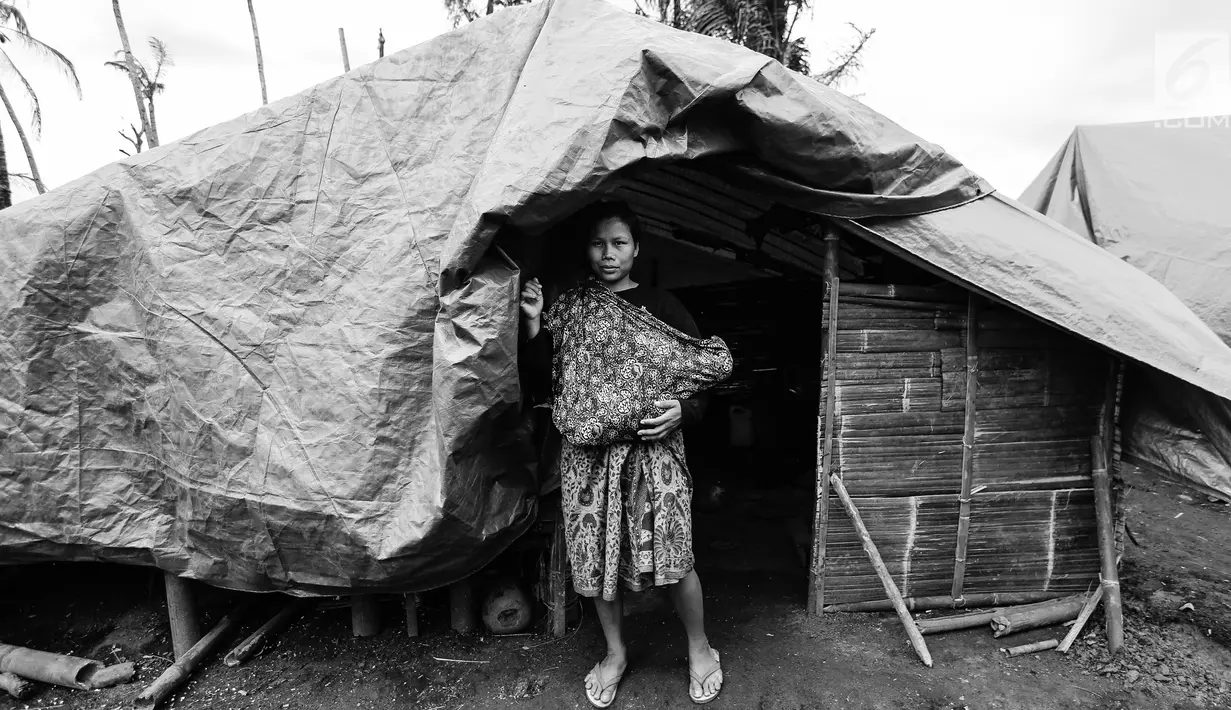 Seorang ibu Suku Baduy Luar menggendong anak di depan rumah bekas kebakaran Kampung Cisaban II, Desa Kanekes, Banten, Kamis (01/6). Kebakaran pada pekan lalu yang menghanguskan 83 rumah Suku Baduy Luar. (Liputan6.com/Fery Pradolo)