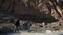 Seorang polisi Hazara mengumpulkan air dari pompa tangan dekat situs patung Buddha raksasa yang dihancurkan oleh Taliban pada 2001 di Provinsi Bamiyan, Afghanistan, 3 Maret 2021. Dua patung Buddha raksasa ini pernah dihancurkan oleh Taliban karena dianggap tidak Islami. (WAKIL KOHSAR/AFP)