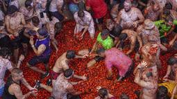Orang-orang yang bersuka ria saling melempar tomat dalam acara tahunan "Tomatina", pesta pertarungan tomat di desa Bunol dekat Valencia, Spanyol, Rabu (31/8/2022). La Tomatina sering dianggap sebagai salah satu pertarungan makanan terbesar di dunia. (AP Photo/Alberto Saiz)
