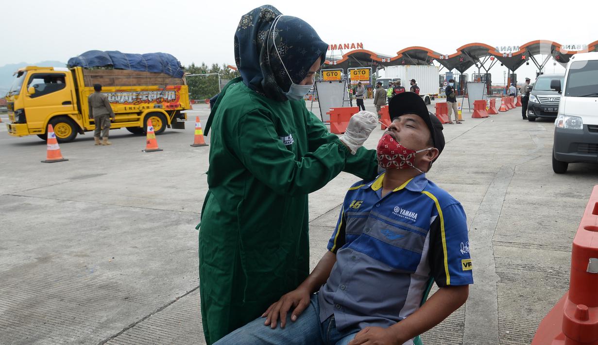Petugas medis melakukan tes COVID-19 terhadap seorang pria di Gerbang Tol Palimanan, Jakarta, Jumat, (7/5/2021). Gerbang Tol Palimanan terpantau sepi pemudik dan didominasi oleh kendaraan angkutan barang pada hari kedua penyekatan. (merdeka.com/Imam Buhori)