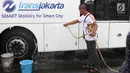 Suporter Persija Jakarta mencuci bus transjakarta di kantor PT Transjakarta, Jakarta, Kamis (13/12). Hal tersebut dilakukan bentuk tanggung jawab atas aksi vandalisme oknum suporter saat Persija meraih Juara Liga 1 2018. (Liputan6.com/Immanuel Antonius)
