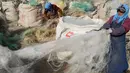 Para nelayan membersihkan jaring ikan yang dibuang untuk didaur ulang di sebuah desa di Lianyungang, di provinsi Jiangsu timur China (17/3/2021). Daur ulang jaring ikan tersebut akan dibuat palet nilon. (STR/AFP/China Out)