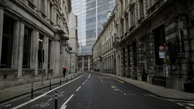 Seorang warga berjalan dengan payung saat hujan ringan pagi pertama penerapan lockdown nasional ketiga di Kota London, Inggris, 5 Januari 2021. Penerapan lockdown nasional ketiga di Inggris berlangsung selama enam minggu. (AP Photo/Matt Dunham)