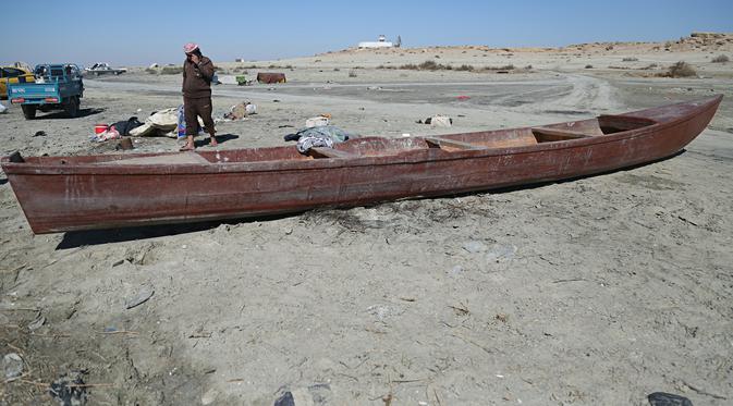 Nelayan berjalan di samping perahunya di tepi Danau Razzaza, juga dikenal sebagai Danau Milh, di provinsi Karbala, Irak, 14 Februari 2022. Danau Razzaza Irak pernah menjadi objek wisata terkenal dengan pemandangan indahnya dan banyak ikan yang menjadi andalan penduduk setempat (AP Photo/Hadi Mizban)