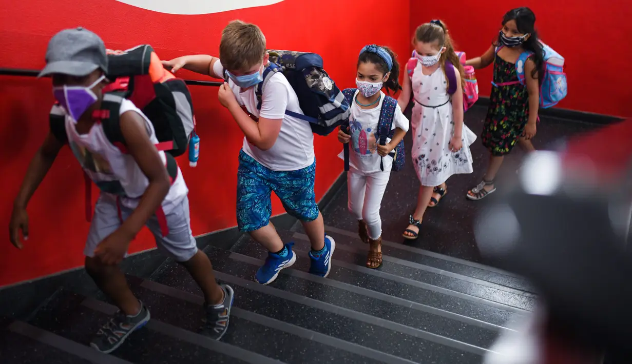 Siswa dengan masker menaiki tangga menuju ruang kelas mereka di sekolah dasar Petri di Dortmund, Jerman, Rabu (12/8/2020). Para siswa di negara bagian Jerman, North Rhine-Westphalia, harus mengenakan masker setiap waktu ketika mereka kembali ke sekolah pada Rabu ini. (Ina FASSBENDER/AFP)