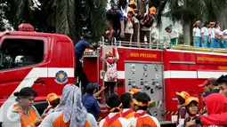 Petugas membantu anak-anak peserta acara Madrasah Siaga Bencana menaiki mobil pemadam kebakaran di hari bebas kendaraan bermotor di kawasan Thamrin, Jakarta, Minggu (22/1). (Liputan6.com/Johan Tallo)