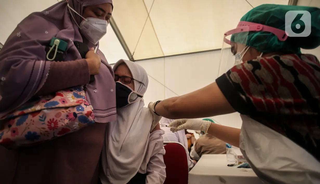 Seorang pelajar didampingi orangtuanya menerima suntikan vaksin covid-19 di Gudang Darurat Nasional Palang Merah Indonesia, Jakarta, Kamis (15/7/2021). Vaksinasi yang menargetkan seribu peserta per hari diselenggarakan hingga 17 Juli 2021. (Liputan6.com/Johan Tallo)
