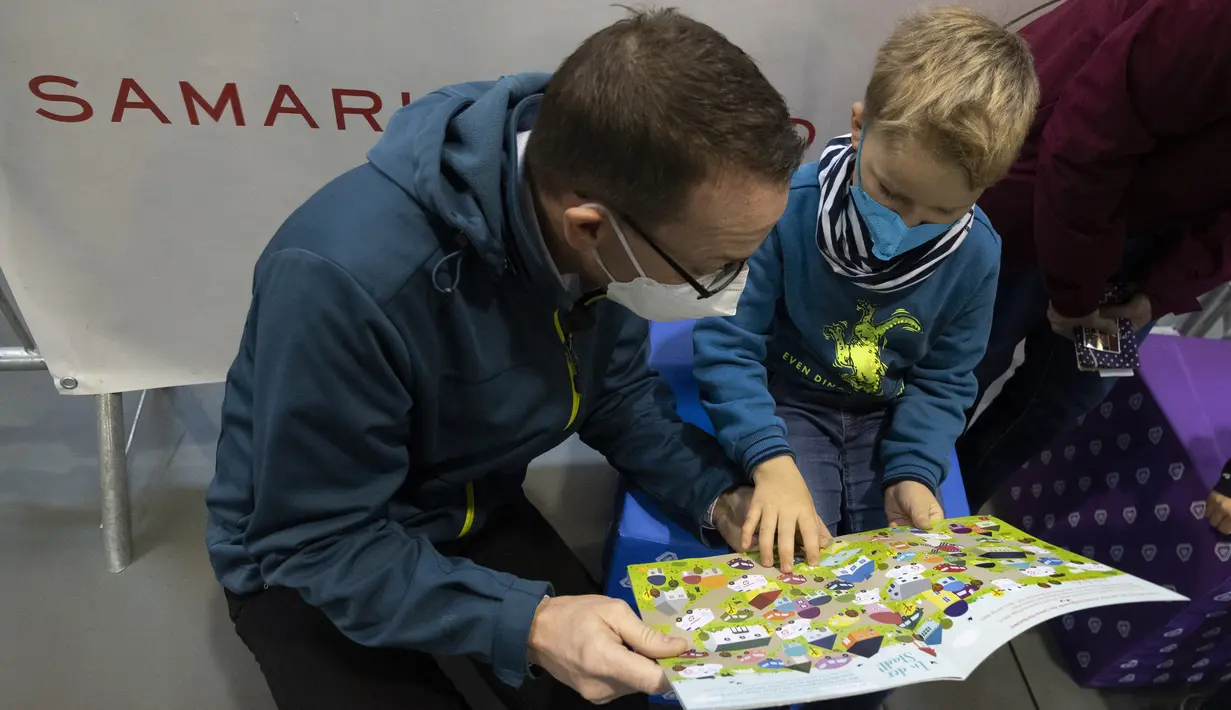Seorang bocah berusia 5 tahun membaca buku setelah menerima suntikan dosis pertama vaksin corona COVID-19 di Wina, Austria, Senin (15/11/2021). Pihak berwenang mulai hari Senin memvaksinasi anak-anak berusia antara 5 dan 11 tahun di ibu kota. (JOE KLAMAR / AFP)