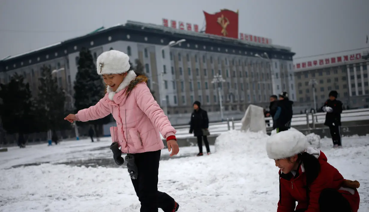 Anak-anak perempuan bermain salju di Kim Il Sung Square, Pyongyang, Korea Utara, Minggu (16/12). Korea Utara saat ini mulai memasuki musim dingin. (AP Photo/Dita Alangkara)