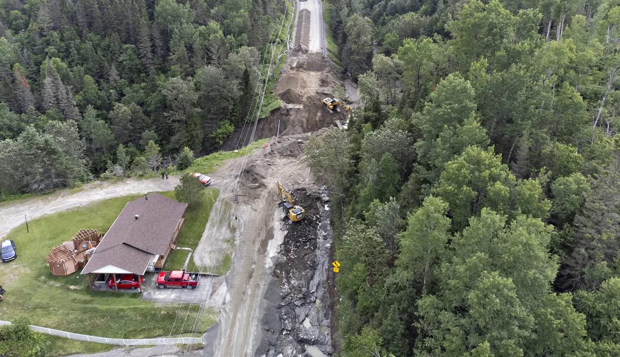 Para kru mulai memperbaiki bagian jalan raya 170 yang tersapu air di Riviere-Eternite, Quebec, Minggu, 2 Juli 2023. (Jacques Boissinot/The Canadian Press via AP)