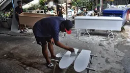 Pekerja toko peti mati Burapha mengecat skateboard, terbuat dari kayu yang digunakan untuk peti mati, di Bangkok pada 19 Maret 2021. Pembuat peti mati di Thailand mengubah kayu peti mati sisa menjadi skateboard murah di tengah booming popularitas olahraga. (Lillian SUWANRUMPHA/AFP)