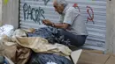 Seorang pria duduk di dekat tumpukan sampah di Santiago (14/11/2019). Protes kekerasan meletus di ibukota Chile, Santiago, pada Selasa ketika mata uang negara itu turun ke level terendah dalam sejarah. (AFP/Javier Torres)