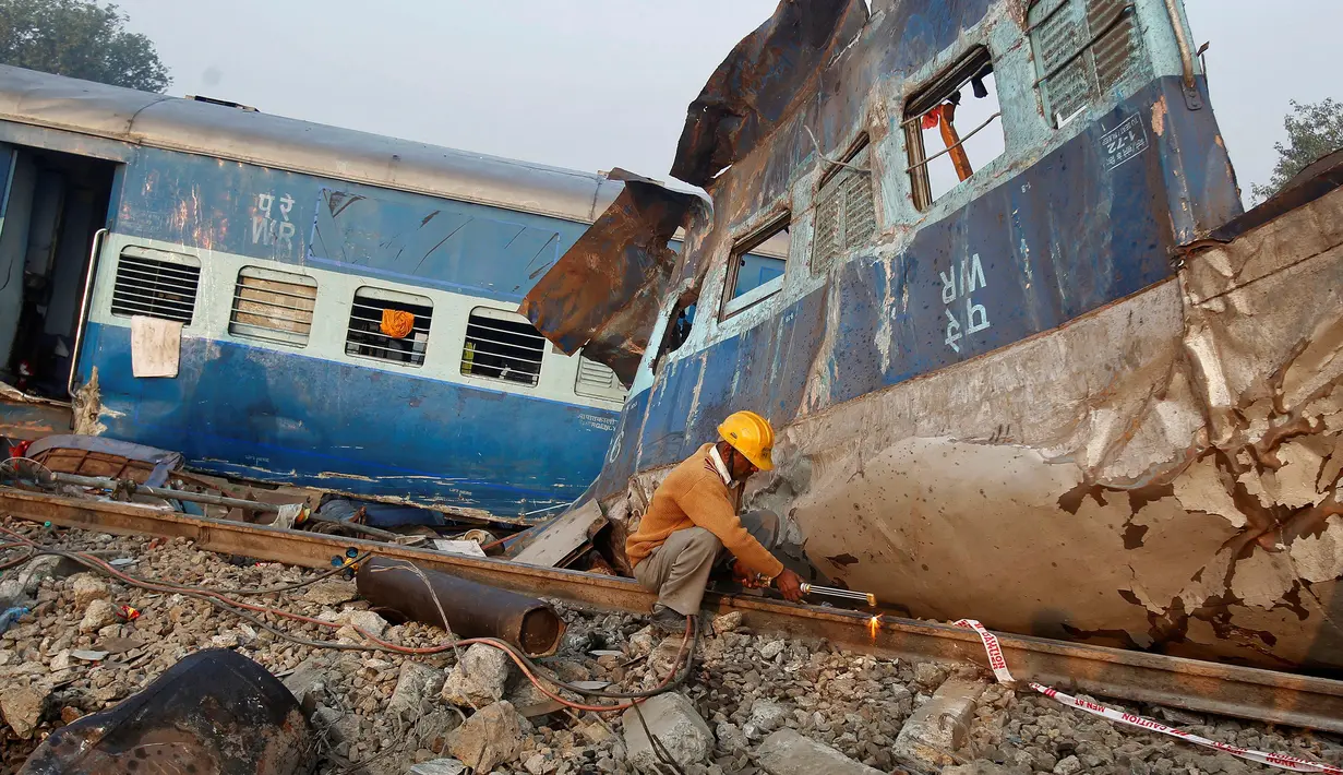 Seorang pekerja memotong rel kereta api untuk mengevakuasi bangkai kereta setelah terjadi kecelakaan  di Kanpur, India (21/11). Menurut keterangan kepolisian setempat, korban yang meninggal tercatat lebih dari 100 orang. (Reuters/ Jitendra Prakash)