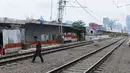 Warga melintasi rel kereta dekat proyek pembangunan jalur dwiganda atau double-double track (DDT) di Jakarta, Jumat (12/4). Proyek pembangunan DDT ditargetkan rampung pada tahun 2021. (Liputan6.com/Herman Zakharia)