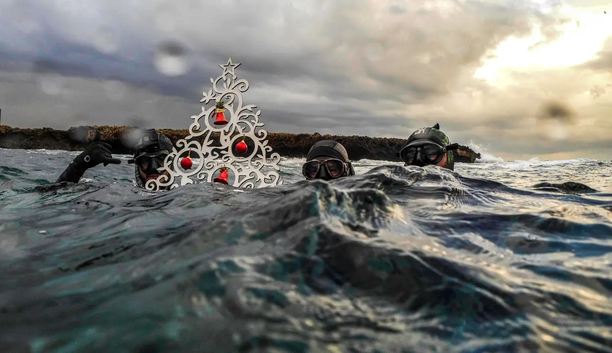 Penyelam berpose saat akan menempatkan pohon Natal di dasar laut lepas pantai Tripoli, Lebanon, Selasa (18/12). Hal ini dilakukan untuk menyambut Natal. (IBRAHIM CHALHOUB/AFP)