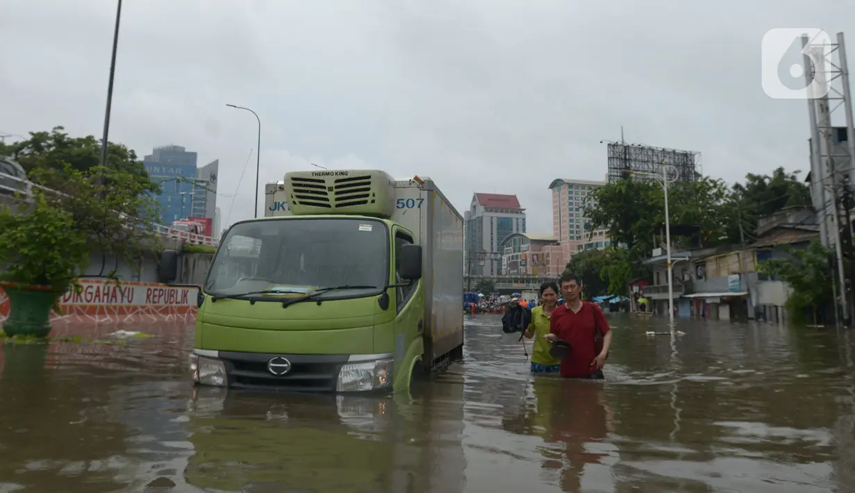 Warga RW 04 Kelurahan Jelambar melintasi banjir di Jakarta, Rabu (1/1/2020). Hujan yang turun saat pergantian tahun baru 2019-2020 menyebabkan sejumlah titik di kawasan Grogol terendam banjir. (merdeka.com/Imam Buhori)