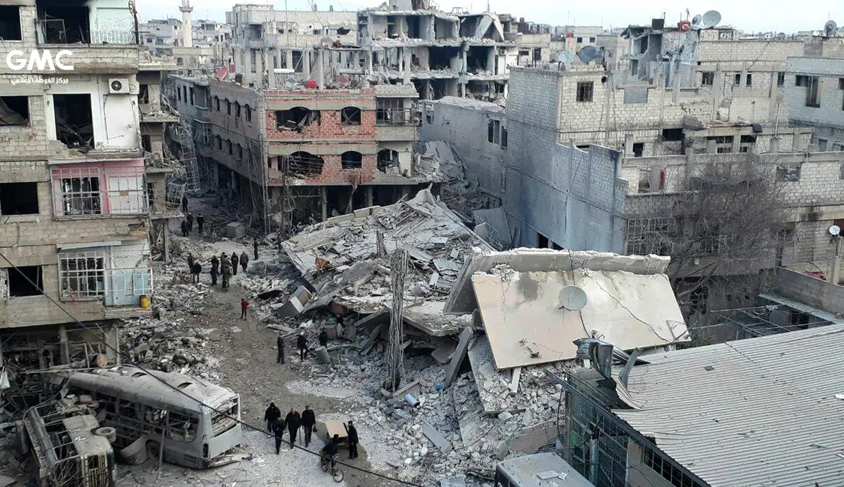 Orang-orang berkumpul di antara bangunan yang hancur saat serangan udara pasukan pemerintah Suriah di Ghouta, pinggiran kota Damaskus, Suriah, Kamis (22/2). (Ghouta Media Center via AP)
