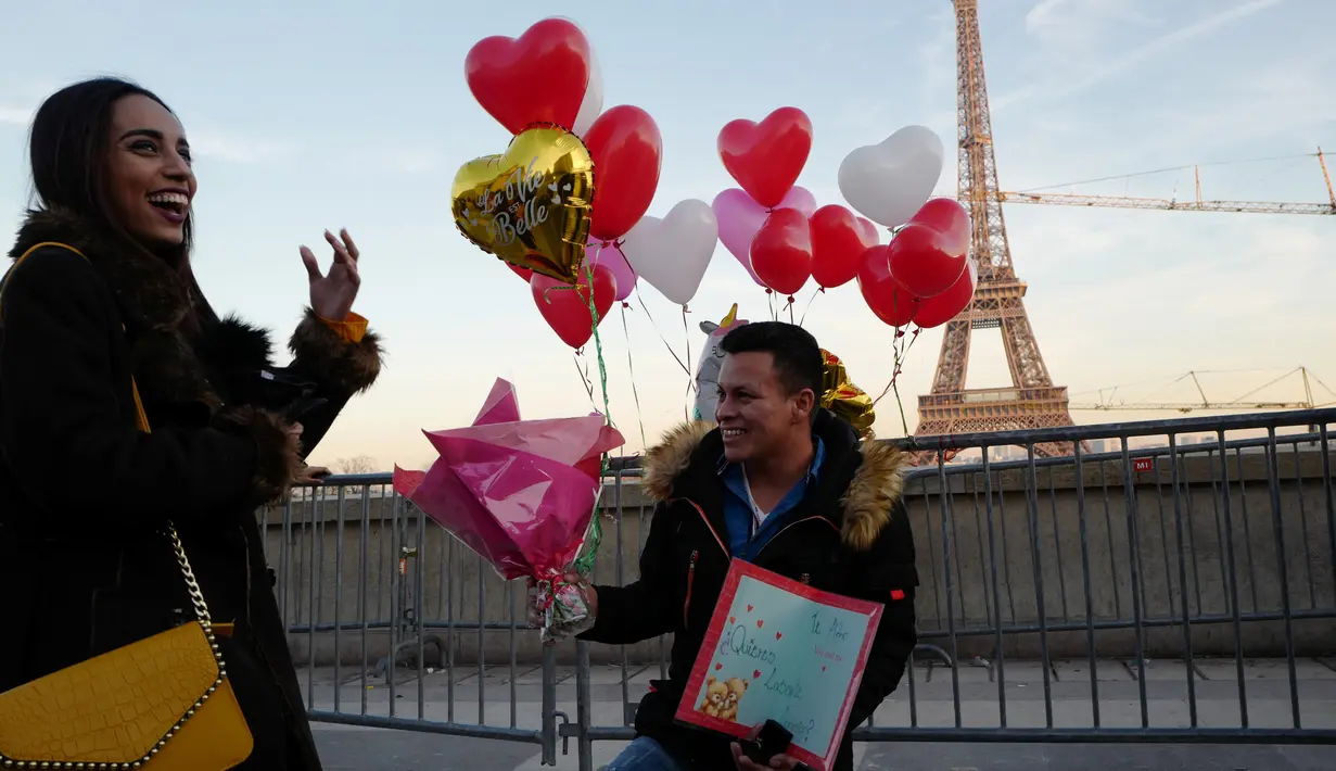 Gerson asal Honduras melamar pasangannya Andry pada Hari Valentine ketika mereka berdiri di Trocadero Plaza dekat Menara Eiffel di Paris, Prancis (14/2). (AFP Photo/Ludovic Marin)