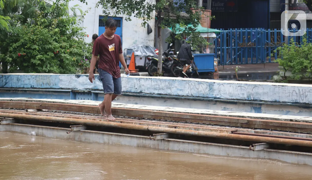 Seorang pria melintas di antara genangan banjir di Jalan dr Sutomo, Pasar Baru, Jakarta, Selasa (25/2/2020). Hujan yang mengguyur Jakarta sejak Senin (24/2) malam membuat sejumlah kali meluap dan menyebabkan banjir. (Liputan6.com/Helmi Fithriansyah)