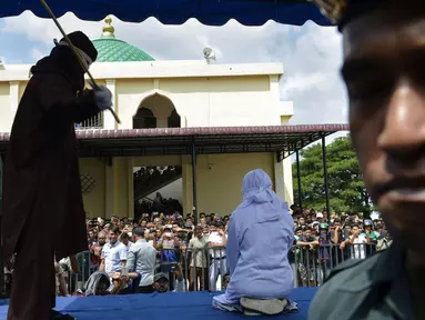 Seorang wanita berusia 19 tahun menjalani hukuman cambuk di depan umum di Banda Aceh (31/1). Dua remaja AS laki-laki (19) dan NS perempuan (19) dicambuk setelah mereka ketahuan berpelukan di depan umum. (AFP Photo/Chaideer Mahyudin)