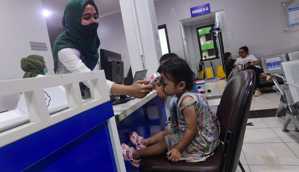 Secara keseluruhan, Pemerintah Provinsi DKI Jakarta saat ini mengelola 44 puskesmas, 267 puskesmas pembantu, dan 31 rumah sakit. Tampak dalam foto, salah satu tenaga medis sedang melakukan pemeriksaan suhu badan anak di Puskesmas Kebayoran Lama, Jakarta, Jumat (9/1/2026). (merdeka.com/Arie Basuki)