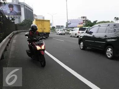 Seorang pengendara motor memasuki jalan tol arah Merak dari persimpangan Taman Anggrek, Jakarta (4/2). Minimnya rambu-rambu lalulintas jalan menuju tol Merak membuat pengendara motor tidak mengetahuinya. (Liputan6.com/Helmi Afandi)