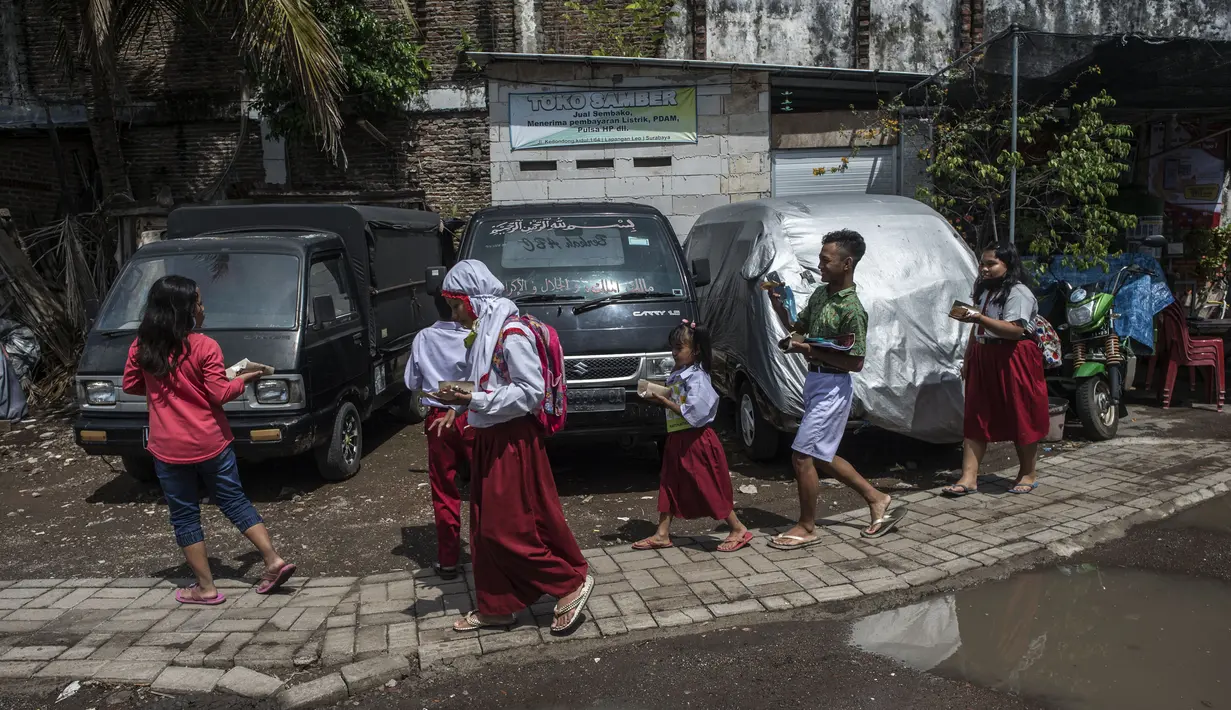Siswa berangkat sekolah untuk mengikuti kegiatan belajar mengajar secara daring di bank sampah yang menyediakan WiFi gratis, di Surabaya, Rabu (15/9/2021). Belajar secara virtual itu sudah berjalan lebih dari setahun lebih di tengah pandemi Covid-19. (JUNI KRISWANTO/AFP)