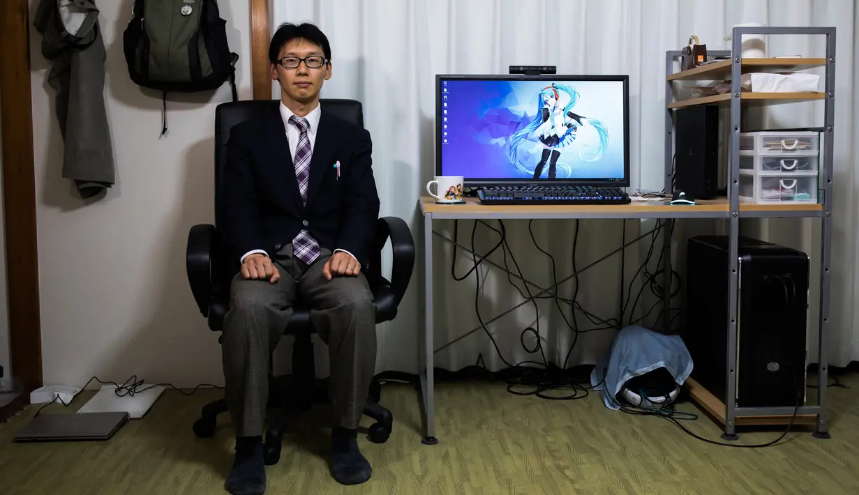 Akihiko Kondo asal Jepang berpose di sebelah layar komputer yang menampilkan gambar aktris virtual, Hatsune Miku di Tokyo, 10 November 2018. Kondo memutuskan menikahi boneka karena mengalami kesulitan berinteraksi di tempat kerjanya. (Behrouz MEHRI/AFP)
